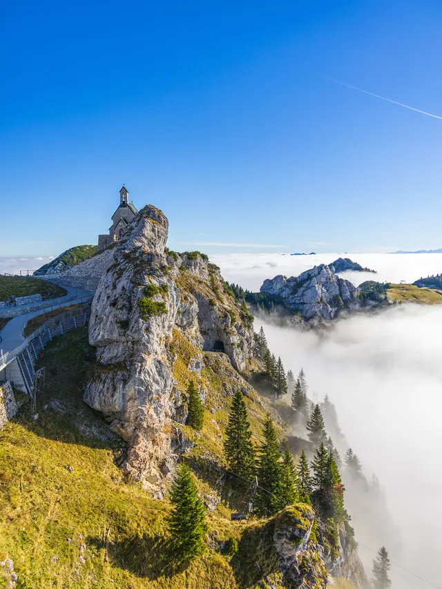 Felsgrat mit Turm über einem Nebelmeer unter blauem Himmel